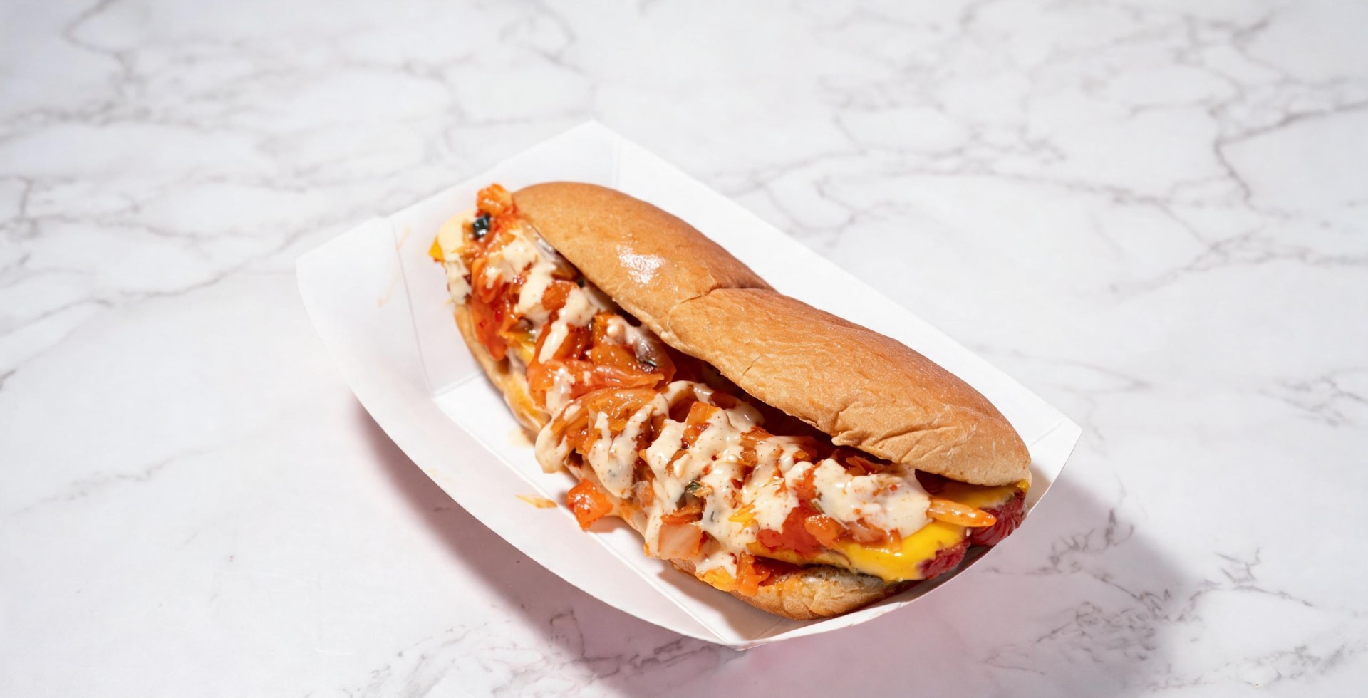 Kimchi hot dog topped with cheese and spicy mayo in a toasted bun