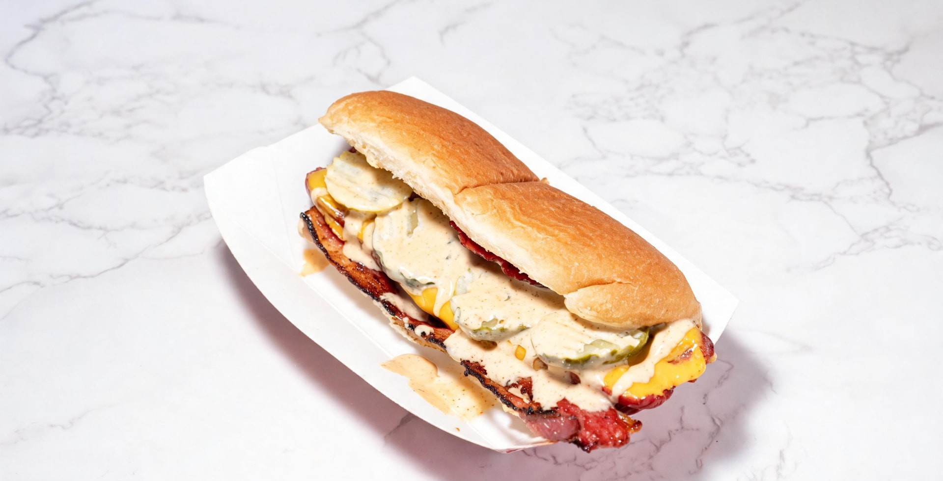 Halal beef bacon wrapped hot dog with melted cheese, pickles and house sauce